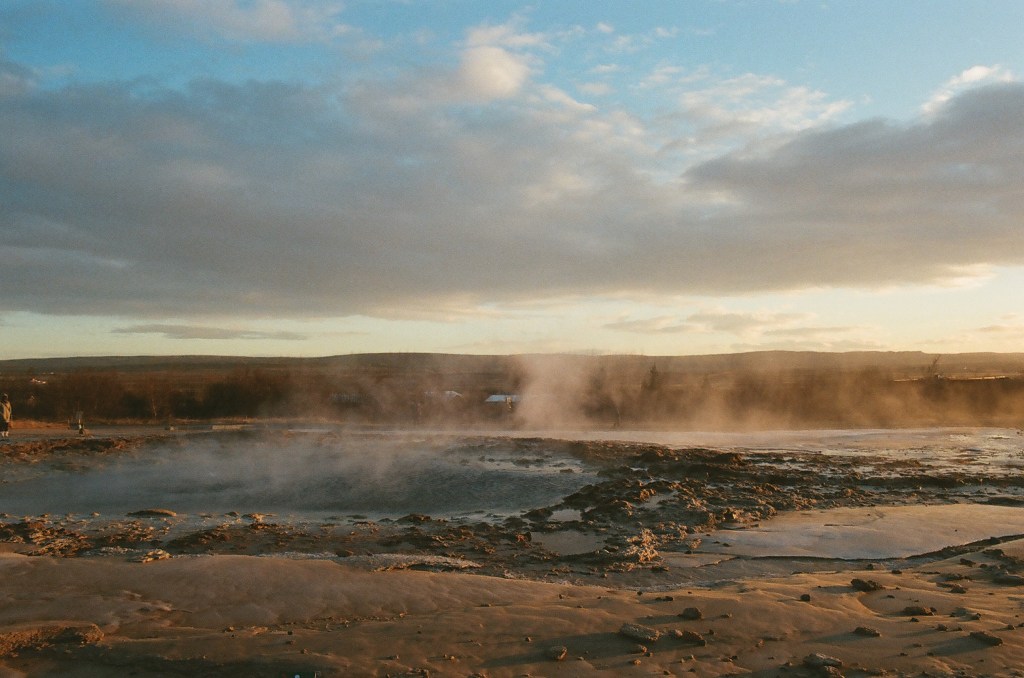A geyser during golden hour in Iceland, letting off steam and roiling.