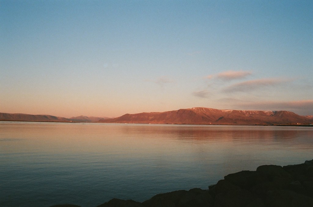 Looking across the water in Reykjavik to mountains in the background during golden hour, as the sun sets.